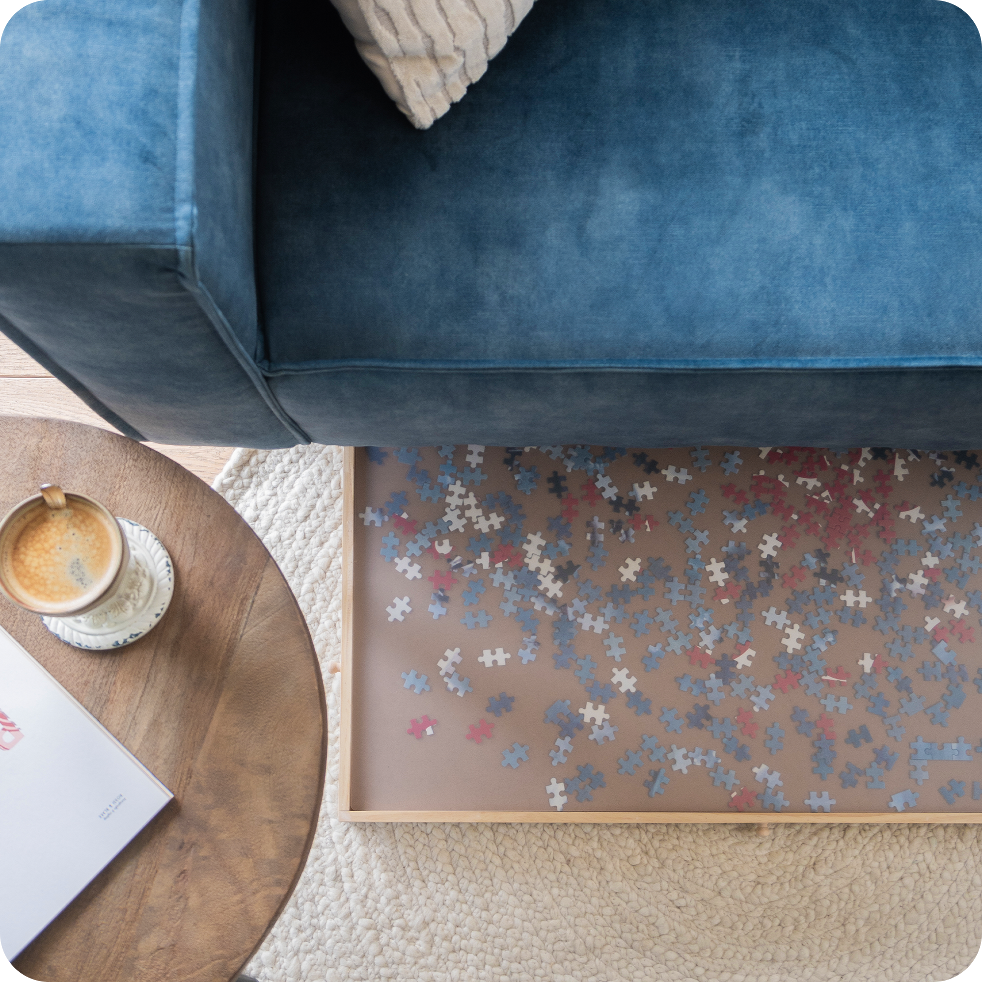 Een bovenaanzicht van een blauwe bank waar je kunt zien dat de puzzelplaat eronder wordt geschoven om opgeborgen te worden. De puzzelplaat heeft een doorzichtige beschermplaat erop.