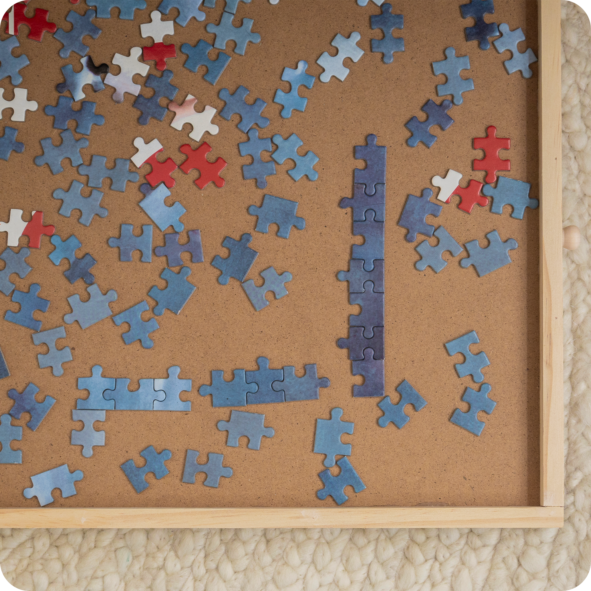 Gedetailleerd bovenaanzicht van de houten puzzelplank met blauwe puzzelstukjes erin.